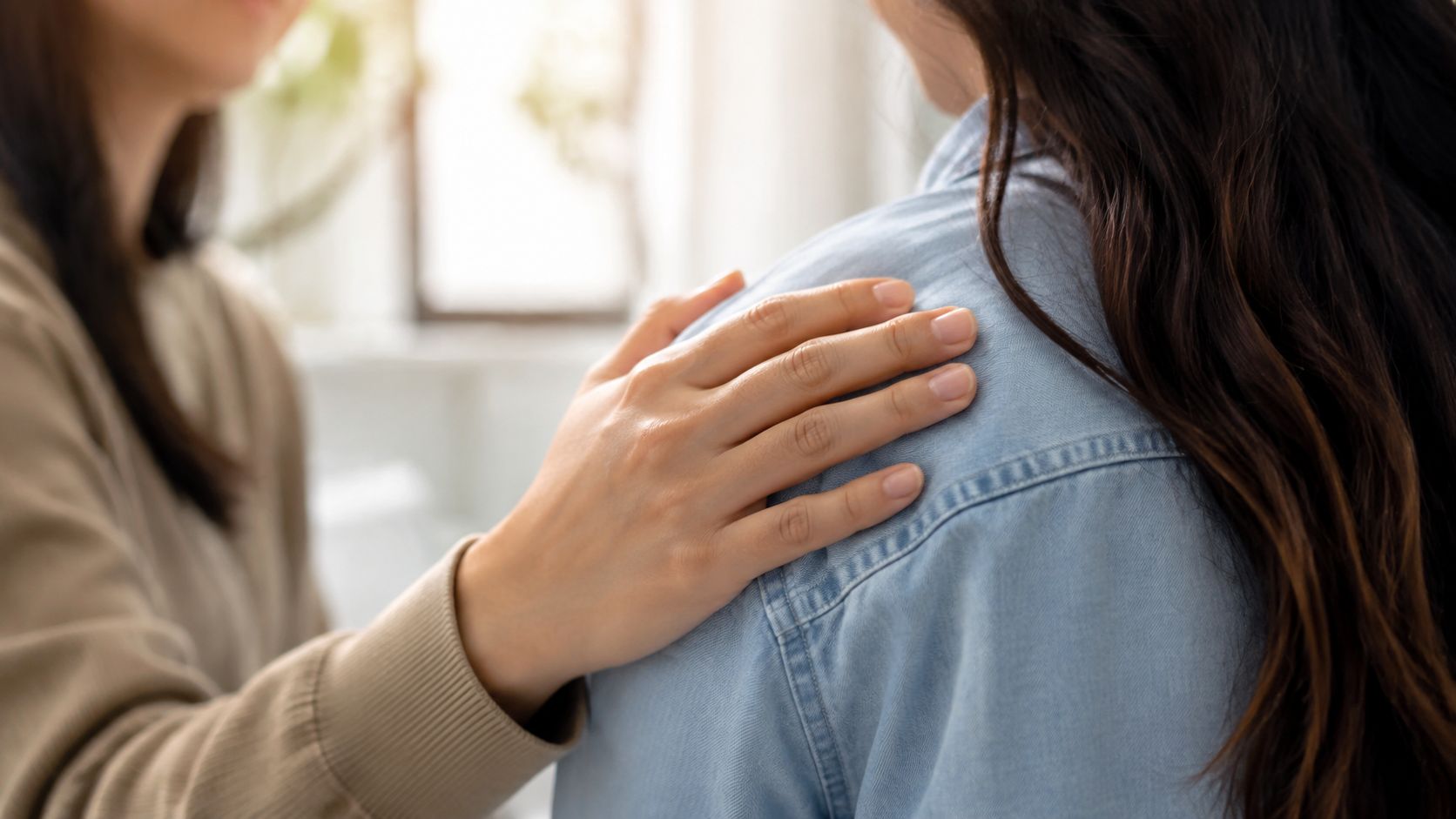 A caring individual placing a comforting hand on someone's shoulder to offer support and empathy.